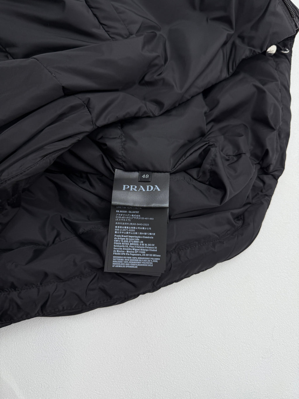 Prada interior care label on dark puffer jacket, fabric close-up