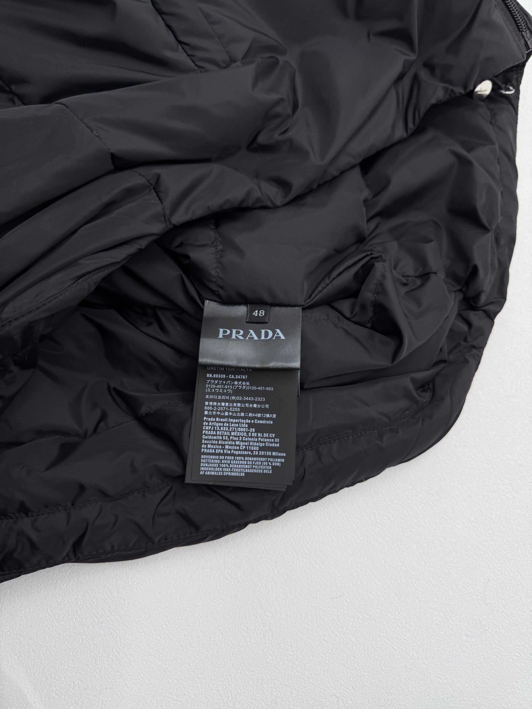Prada interior care label on dark puffer jacket, fabric close-up