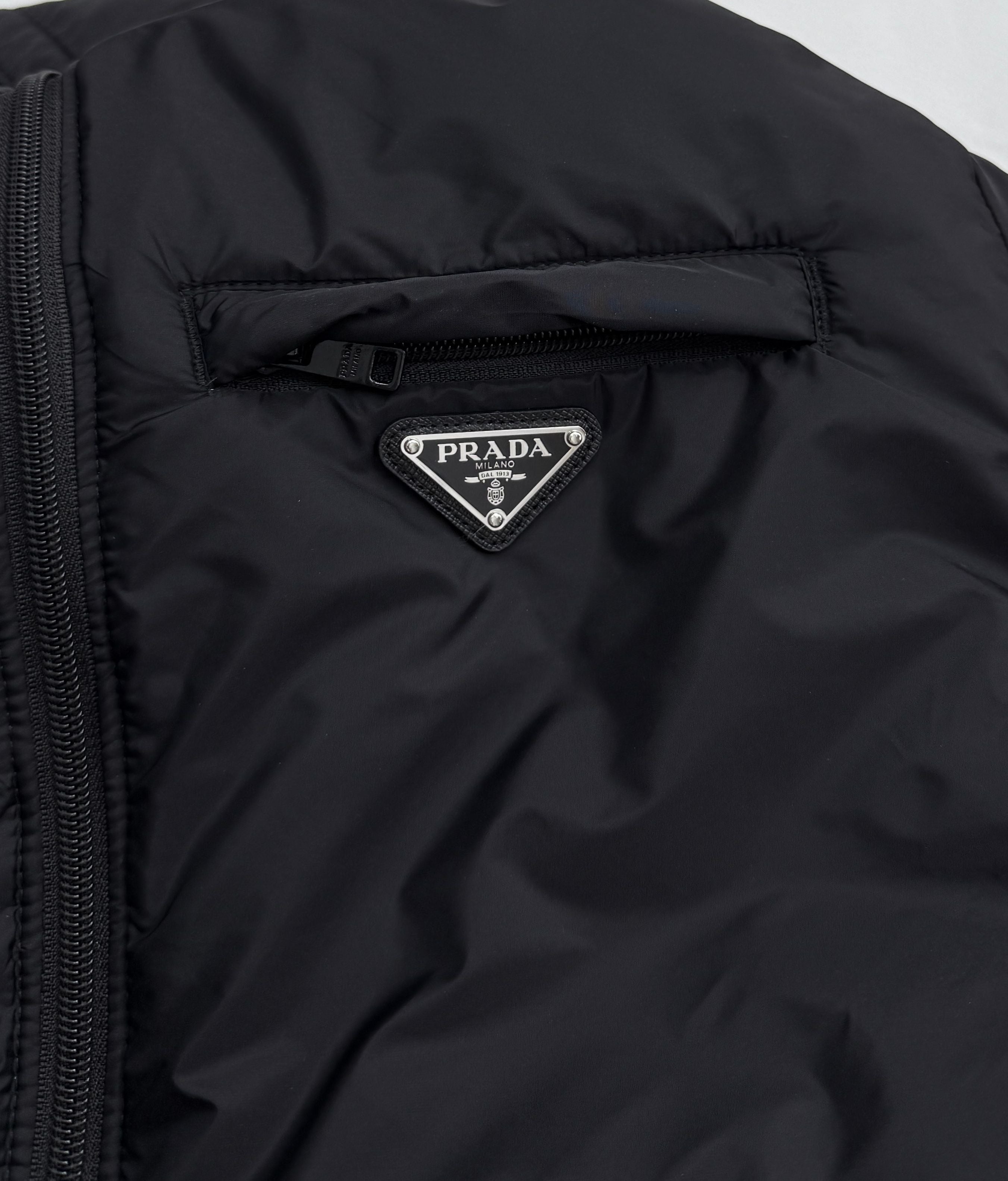 Prada triangular logo patch on dark hooded puffer jacket