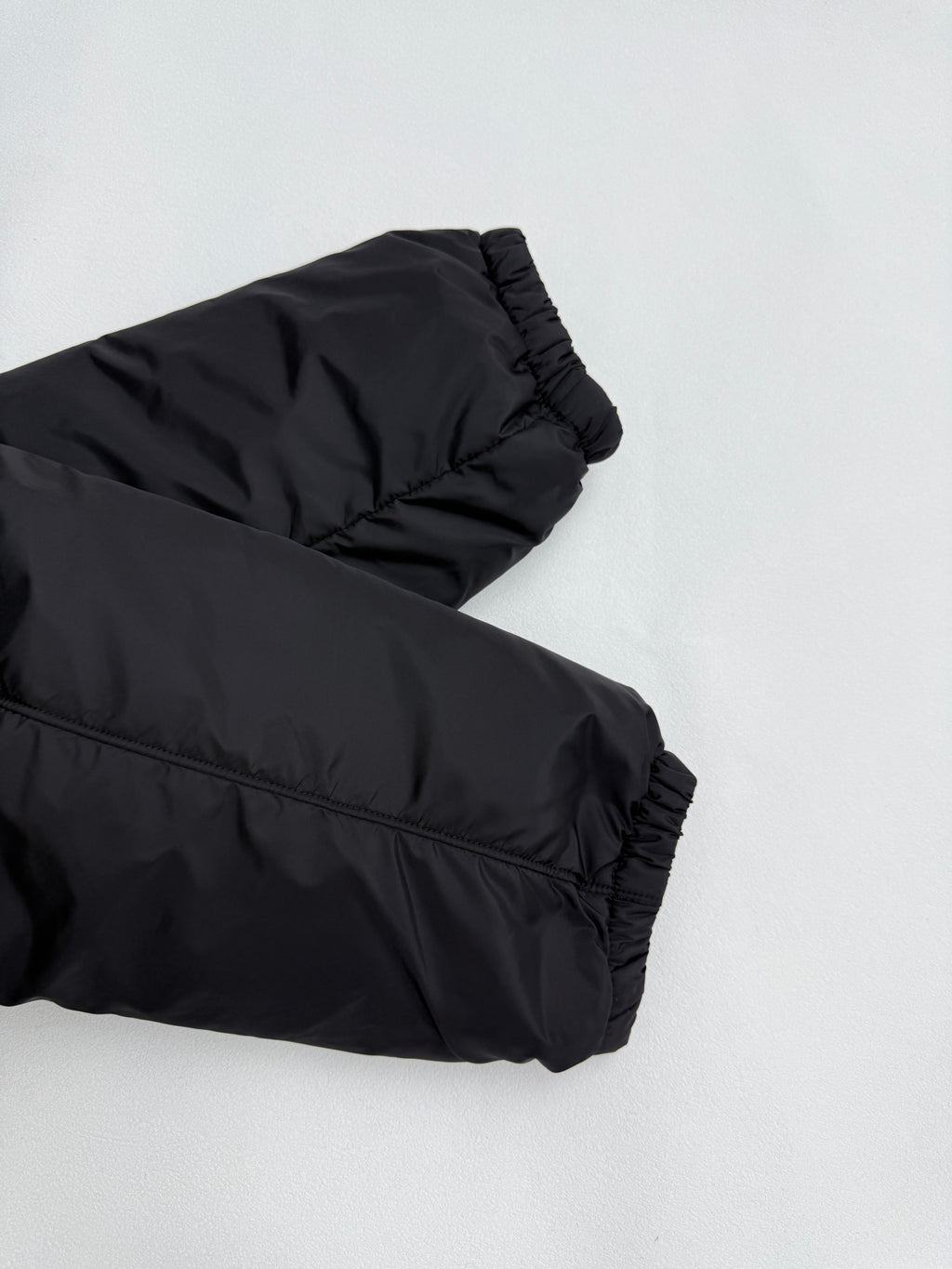 Prada puffer jacket sleeve cuff, dark black, angled close-up