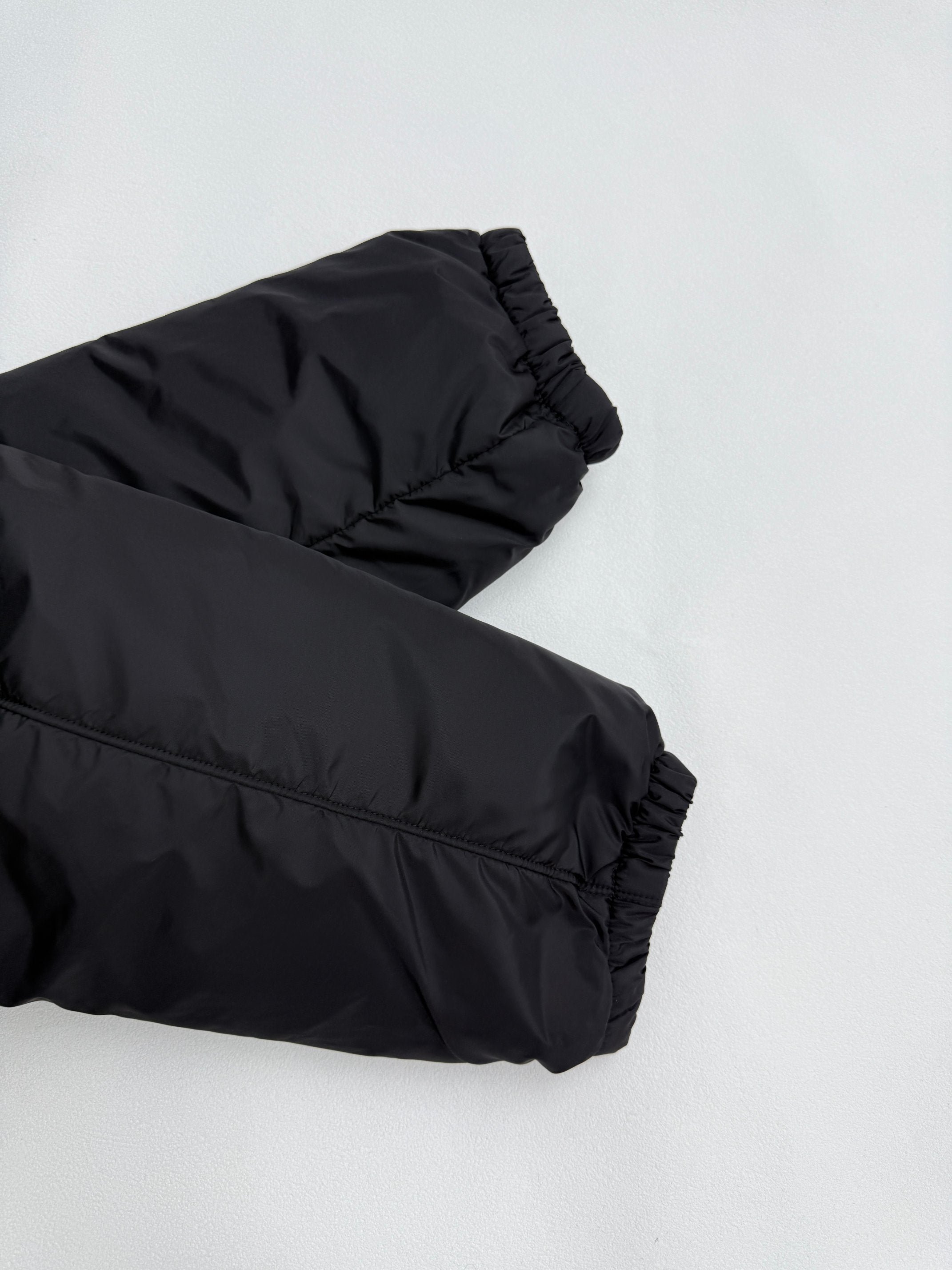 Prada puffer jacket sleeve cuff, dark black, angled close-up