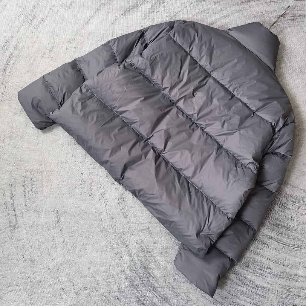 Gray Balenciaga puffer jacket laid out, back showing horizontal quilted panels.