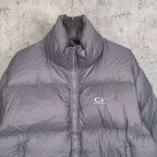 Gray Balenciaga puffer jacket front close-up with high collar and zipper logo.