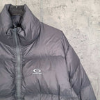 Gray Balenciaga puffer jacket front close-up with high collar, zipper placket, logo.
