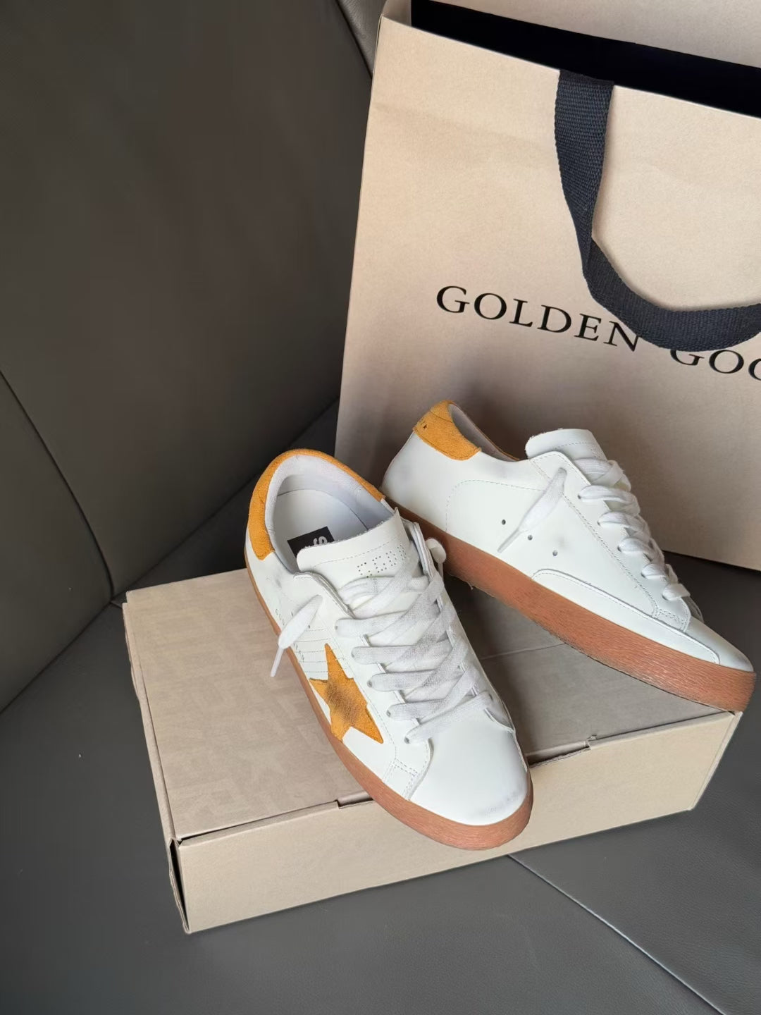 Golden Goose low-top sneakers, white pair with gold star detail and orange-brown sole