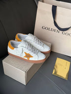 Golden Goose low-top sneakers, white with gold star detail and orange-brown outsole