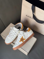 Golden Goose low-top sneakers, side view showing gold star and orange-brown sole
