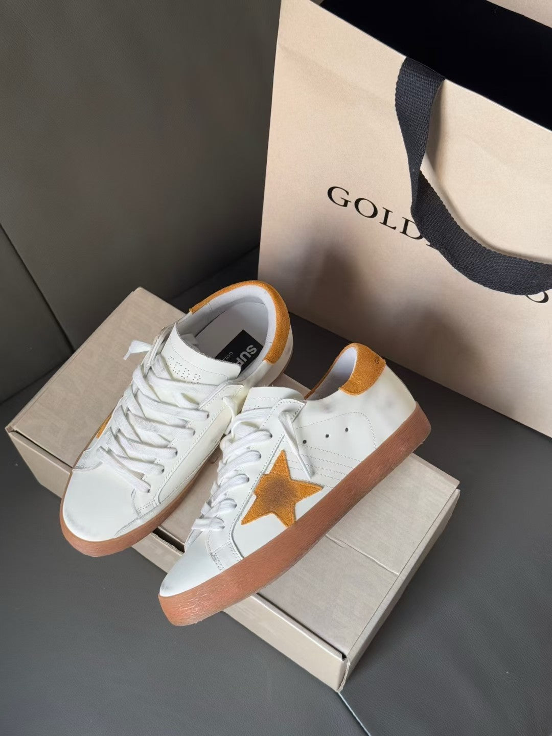 Golden Goose low-top sneakers, side view showing gold star and orange-brown sole