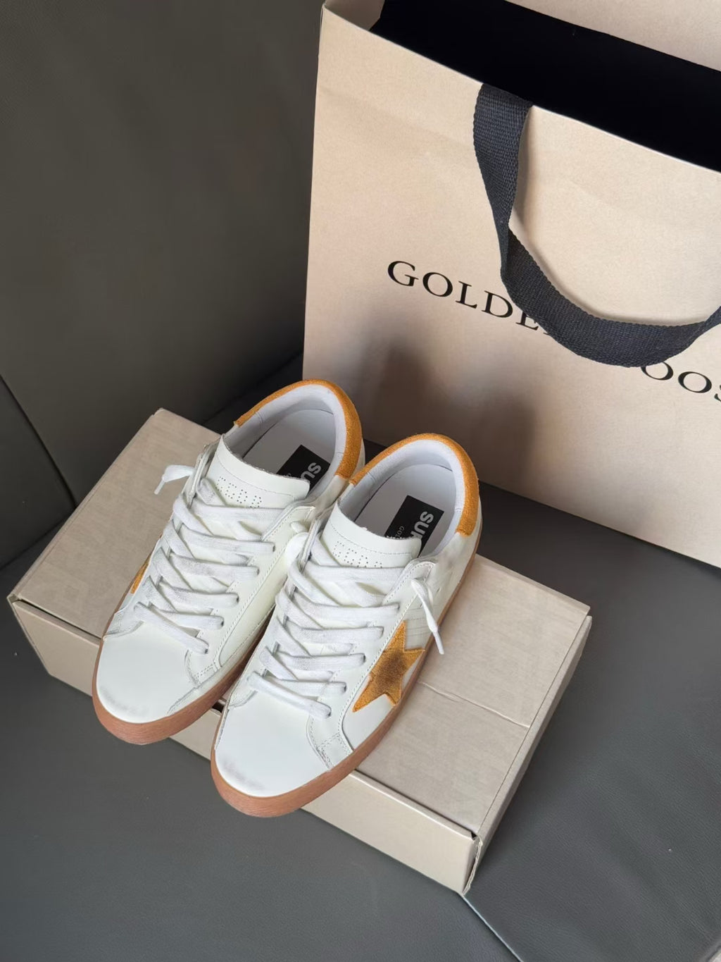 Golden Goose low-top sneakers, front close-up with gold star and white lace-up upper