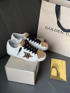 White low-top sneakers with black laces, gold accents, and leopard print panel