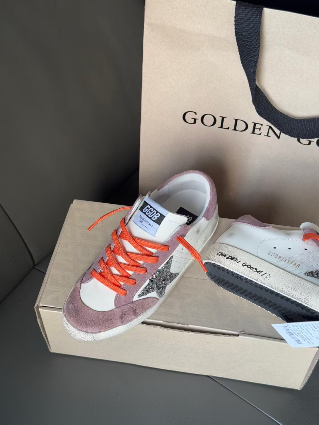 Golden Goose low-top sneakers pair view, white upper, mauve heel, orange laces, star