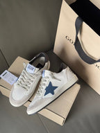 White sneakers with blue star emblem and black heel, shown at side angle with tags