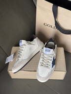 White low-top sneakers with blue star detail and gray laces, placed on shoebox
