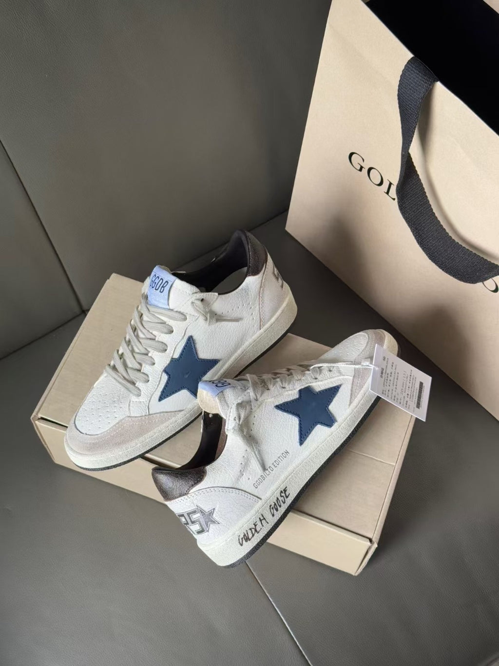White sneakers with blue star emblem and gray laces, front view with logo tags