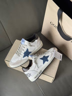 White sneakers with blue star emblem and gray laces, front view with logo tags