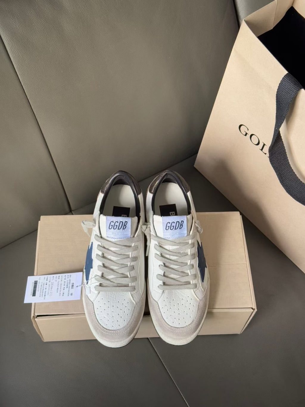White low-top sneakers with blue star patch, gray laces, front view on boxes