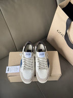 White low-top sneakers with blue star patch, gray laces, front view on boxes