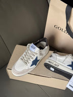White sneakers with blue star patch and black heel trim on beige box