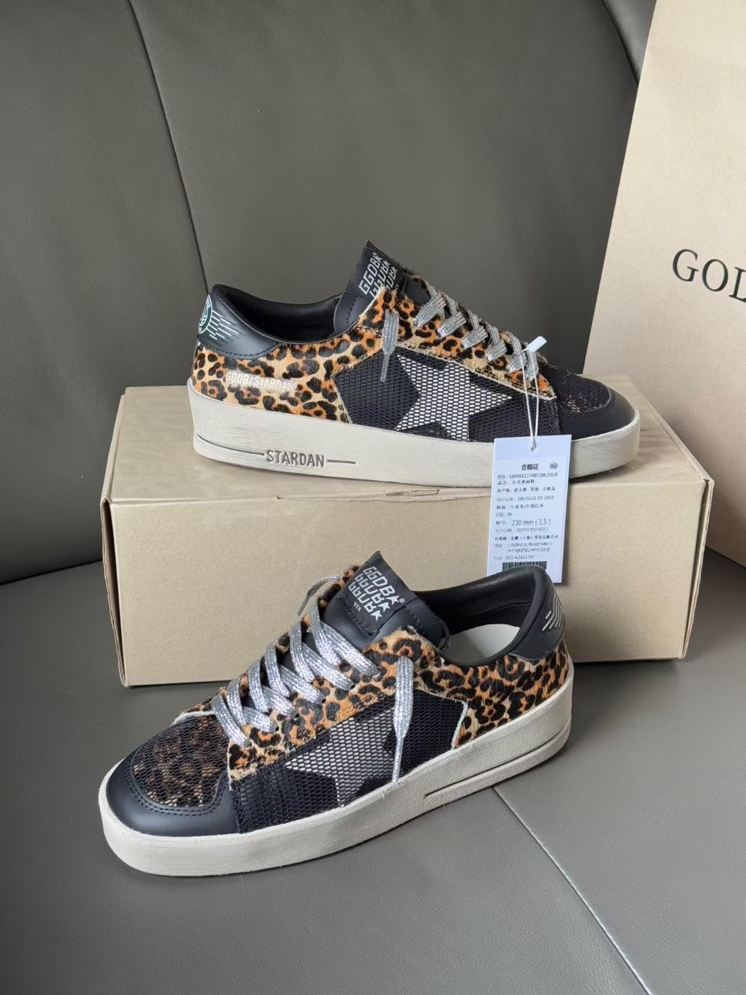 Leopard-print low-top lace-up sneakers on a shoebox, dark uppers and white rubber sole