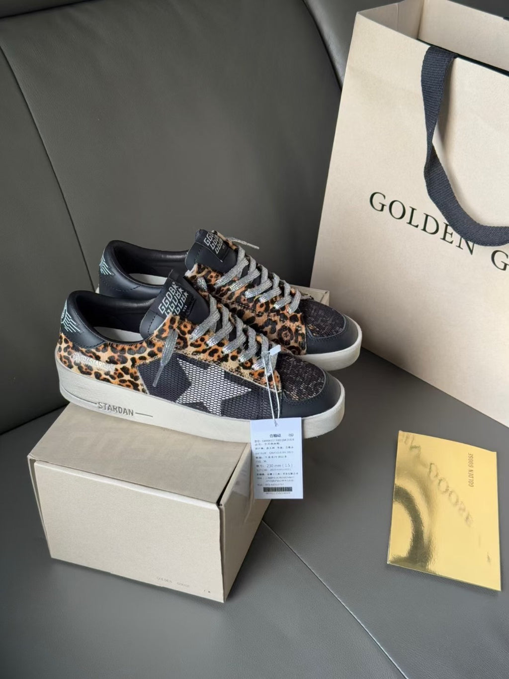 Low-top leopard-print sneakers with dark uppers and white soles, shown with shoebox