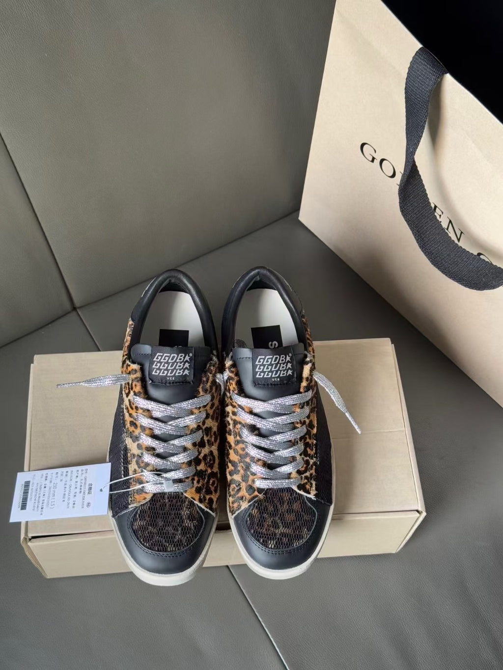 Pair of low-top leopard-print sneakers with dark uppers and white lace-up trim