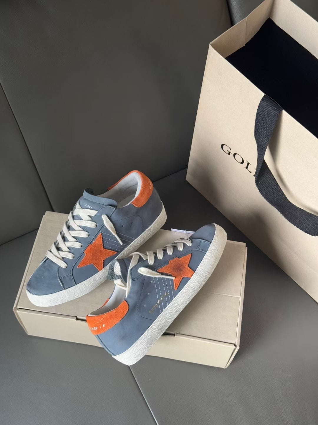 Pair of light blue low-top Golden Goose sneakers with orange star applique and white sole