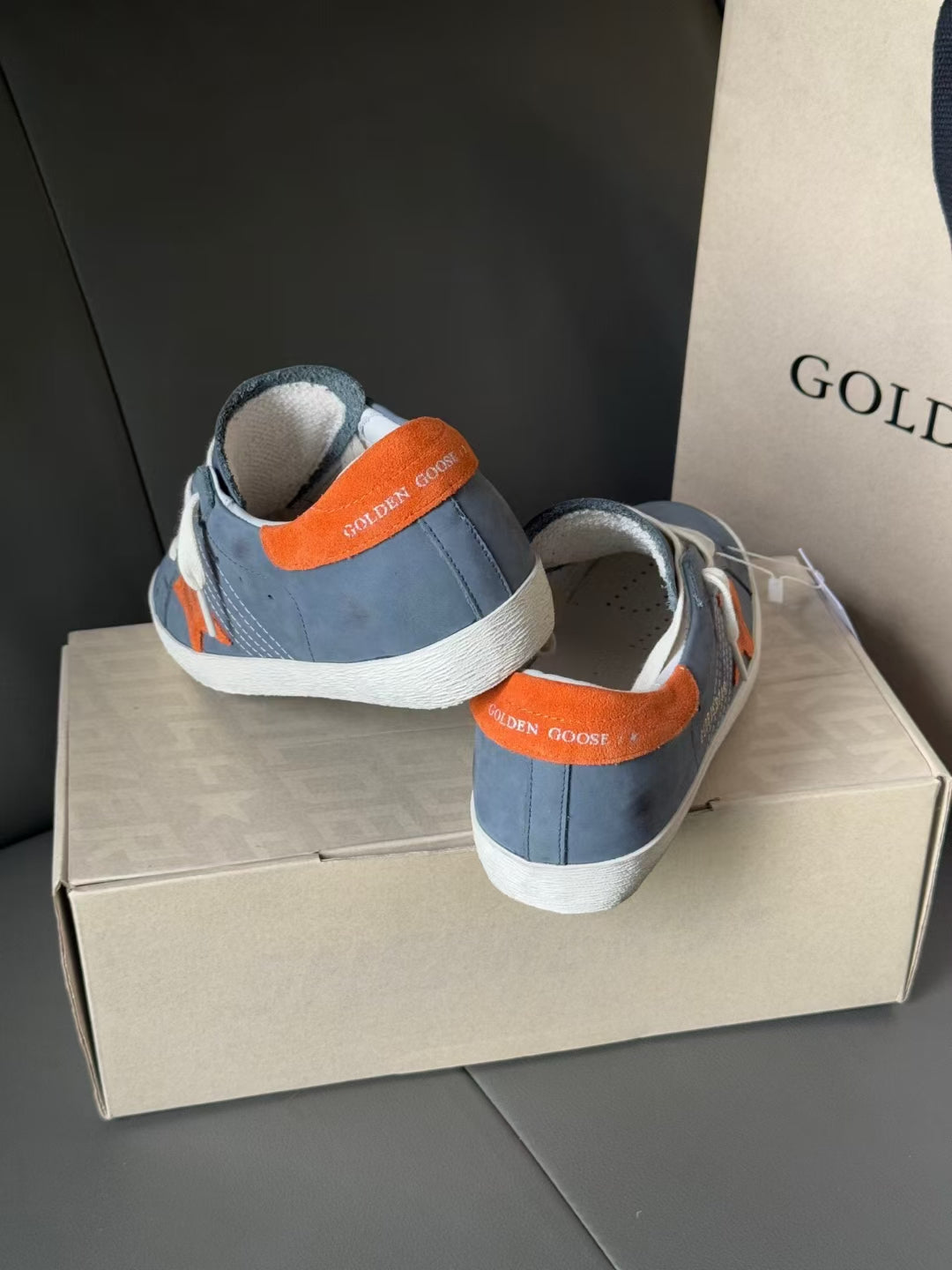 Golden Goose back view sneakers in blue with orange heel tabs and white rubber sole.