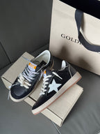 Pair of low-top sneakers, navy with white star, lace-up, gum sole, on shoebox