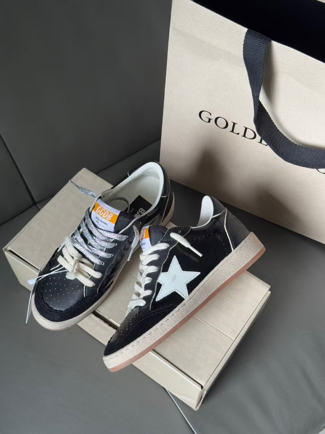 Pair of low-top sneakers, navy with white star, lace-up, gum sole, on shoebox