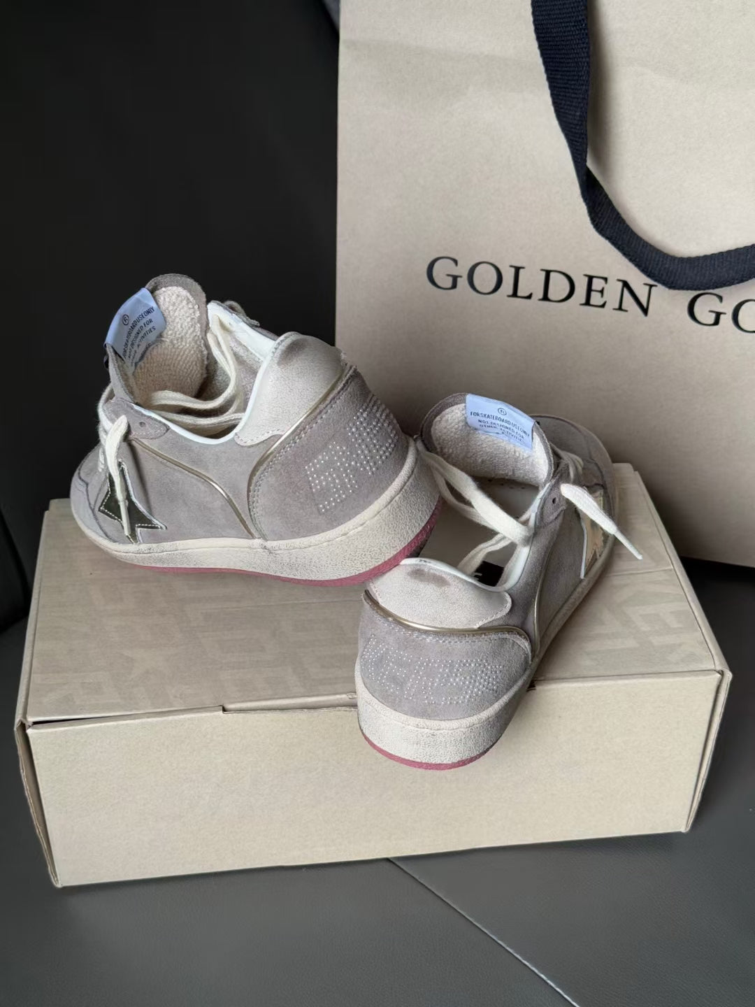 Light gray suede-look sneakers with metallic star detail, white laces, pink heel strip