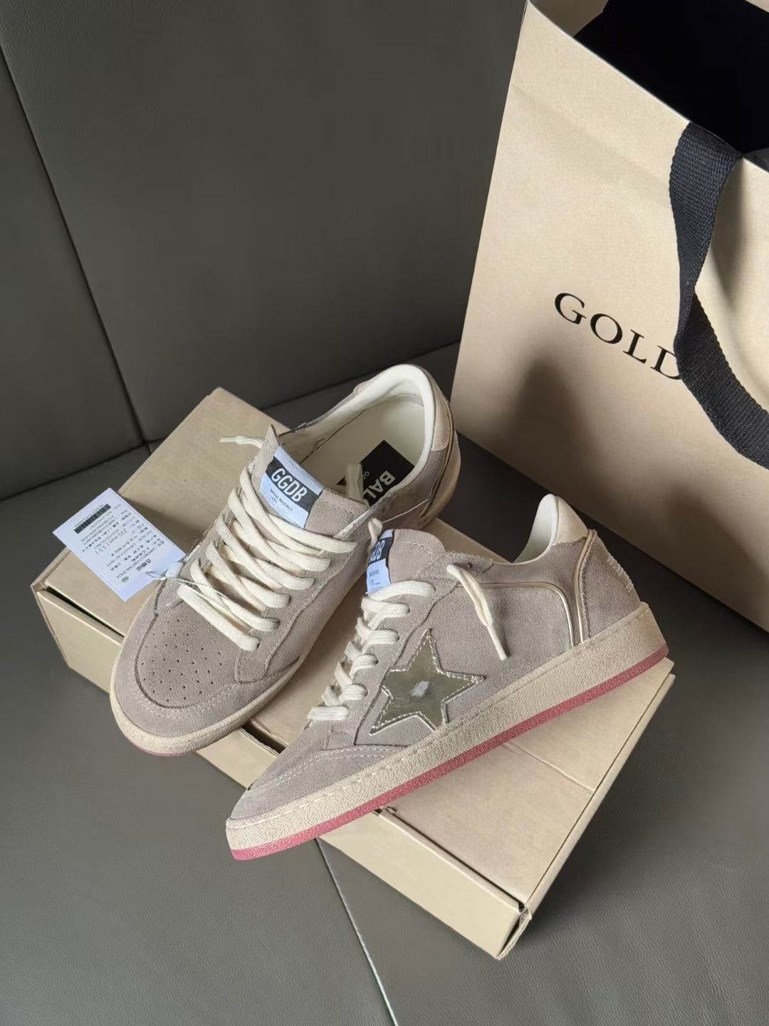 Golden Goose sneakers on shoebox, light gray uppers with pink-red sole trim