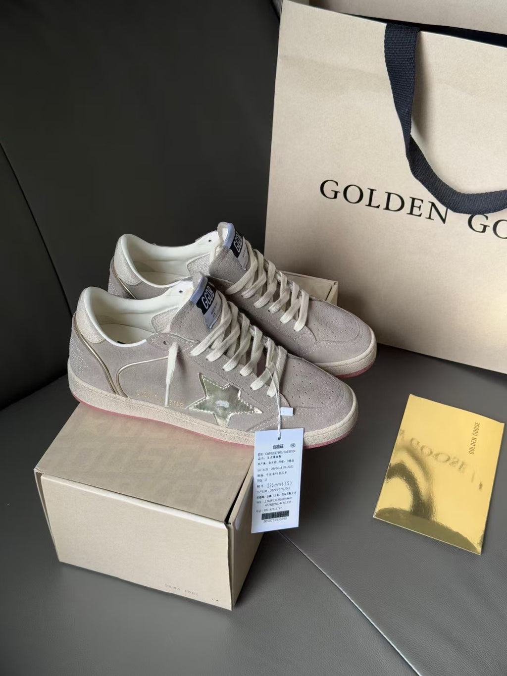 Light gray low-top sneakers with perforated toe and metallic star detail, pink sole edge