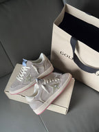 Golden Goose low-top sneakers, light gray with pink-red outsole stripe, set on box