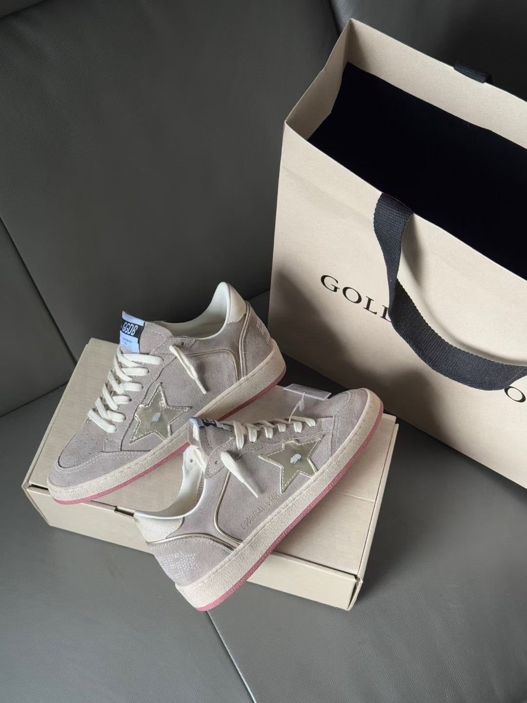 Golden Goose low-top sneakers, light gray with pink-red outsole stripe, set on box