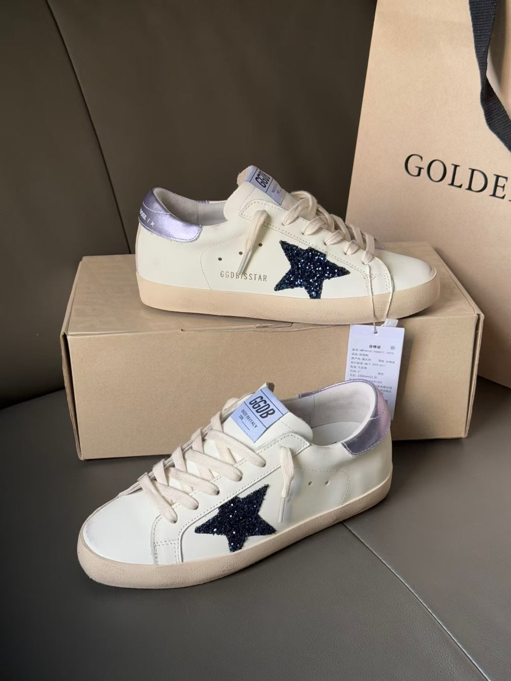 Pair of luxury sneakers, white with navy star and lace-up front, on box