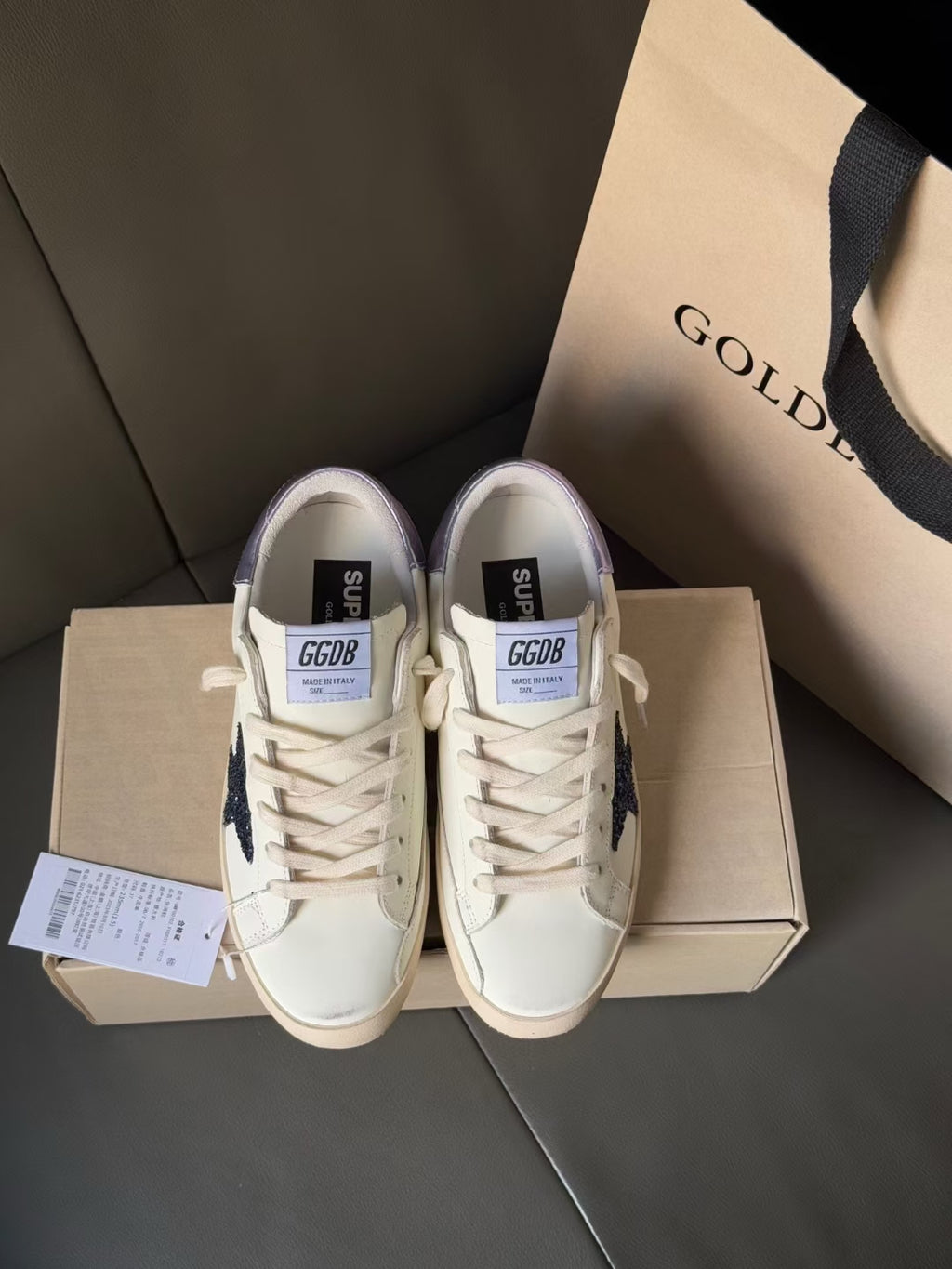 Front view luxury sneakers, white with navy star and lace-up upper, on box