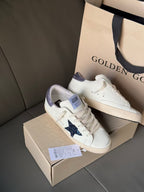 Luxury lace-up sneakers, white with navy star and lavender accents, on box
