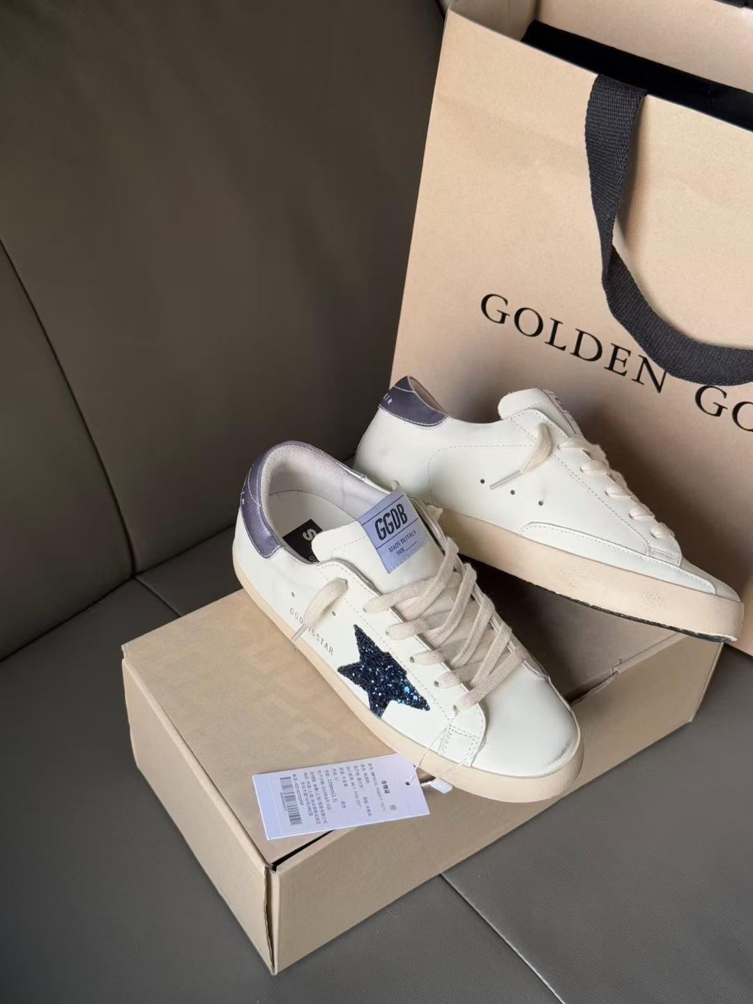 Luxury lace-up sneakers, white with navy star and lavender accents, on box