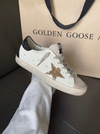 White low-top sneakers with gold glitter star and dark glitter heel tabs