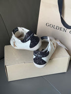 White sneakers with gold star logo and dark glitter heel collar