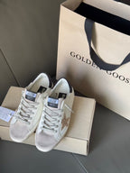 White lace-up sneakers with gold glitter star and dark heel accents, boxed
