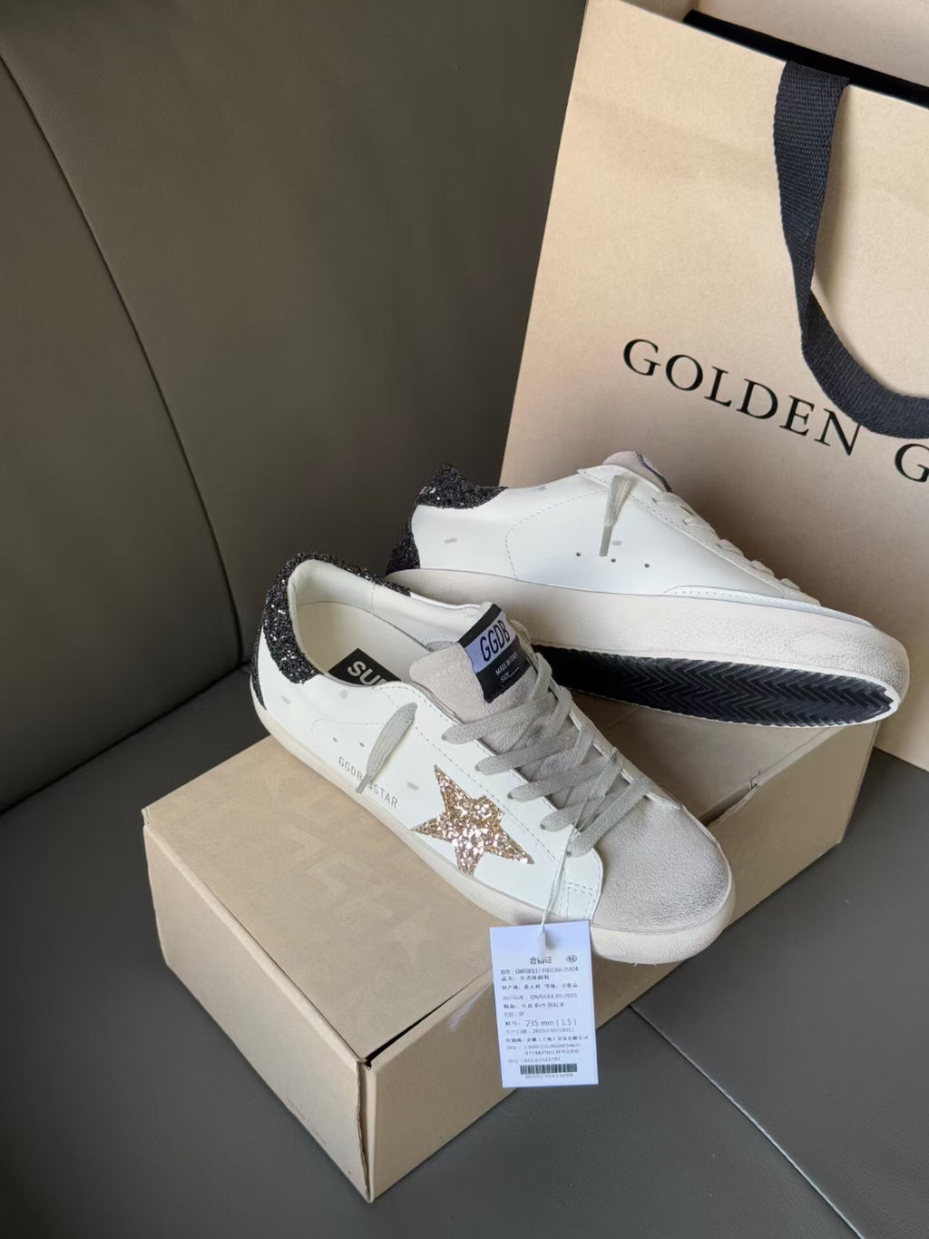 White low-top sneakers with gold glitter star patch and dark heel trim