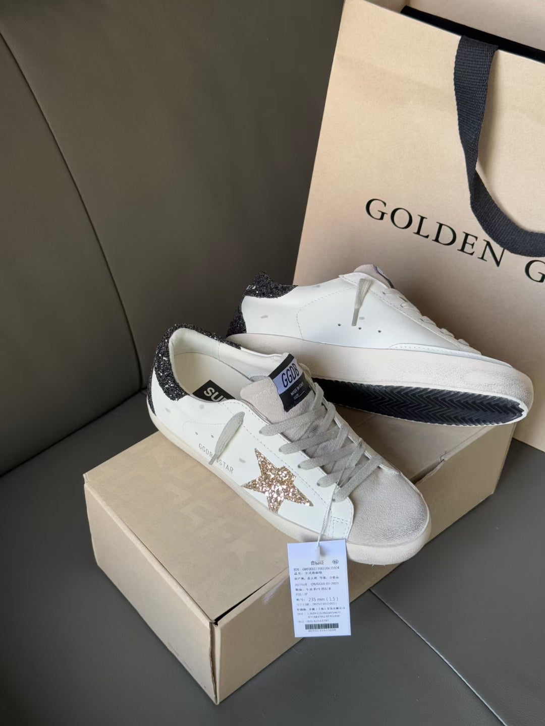 White low-top sneakers with gold glitter star patch and dark heel trim