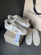 White sneakers with glitter star side panels and plush collars, next to fuzzy shoe liners