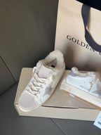 White sneakers with glitter star branding and plush lining, placed on shoe boxes