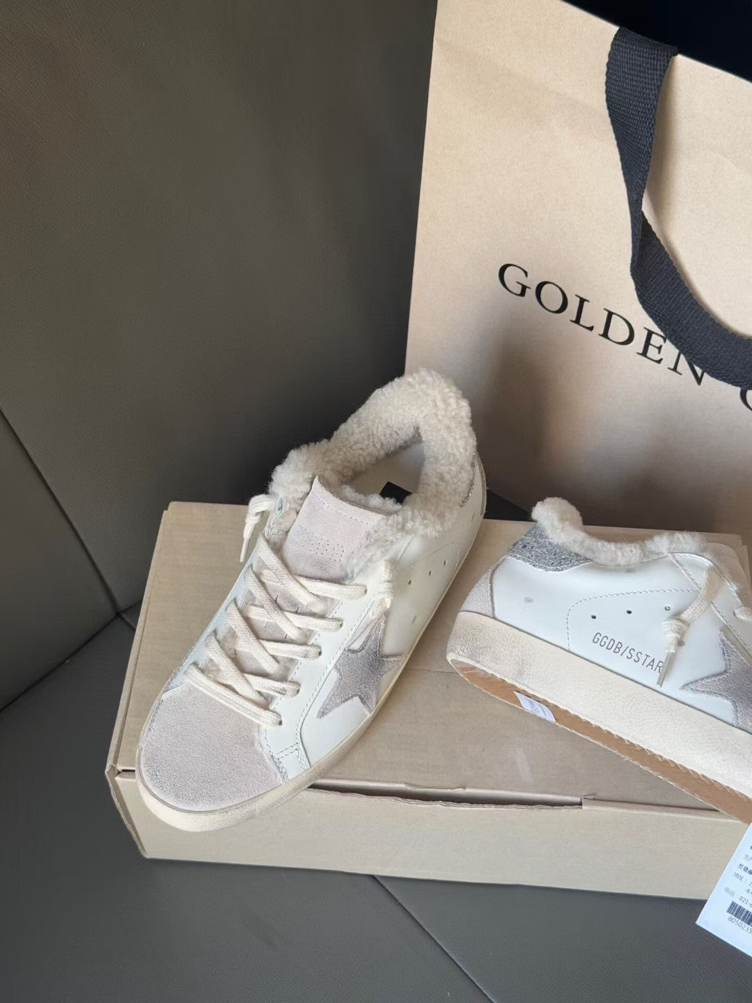 White sneakers with glitter star branding and plush lining, placed on shoe boxes