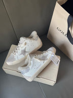 White lace-up sneakers with glitter star accents and plush lining, on open shoe box
