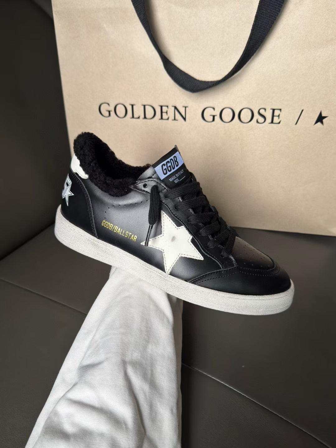 Black low-top leather sneakers with white sole and side star logo