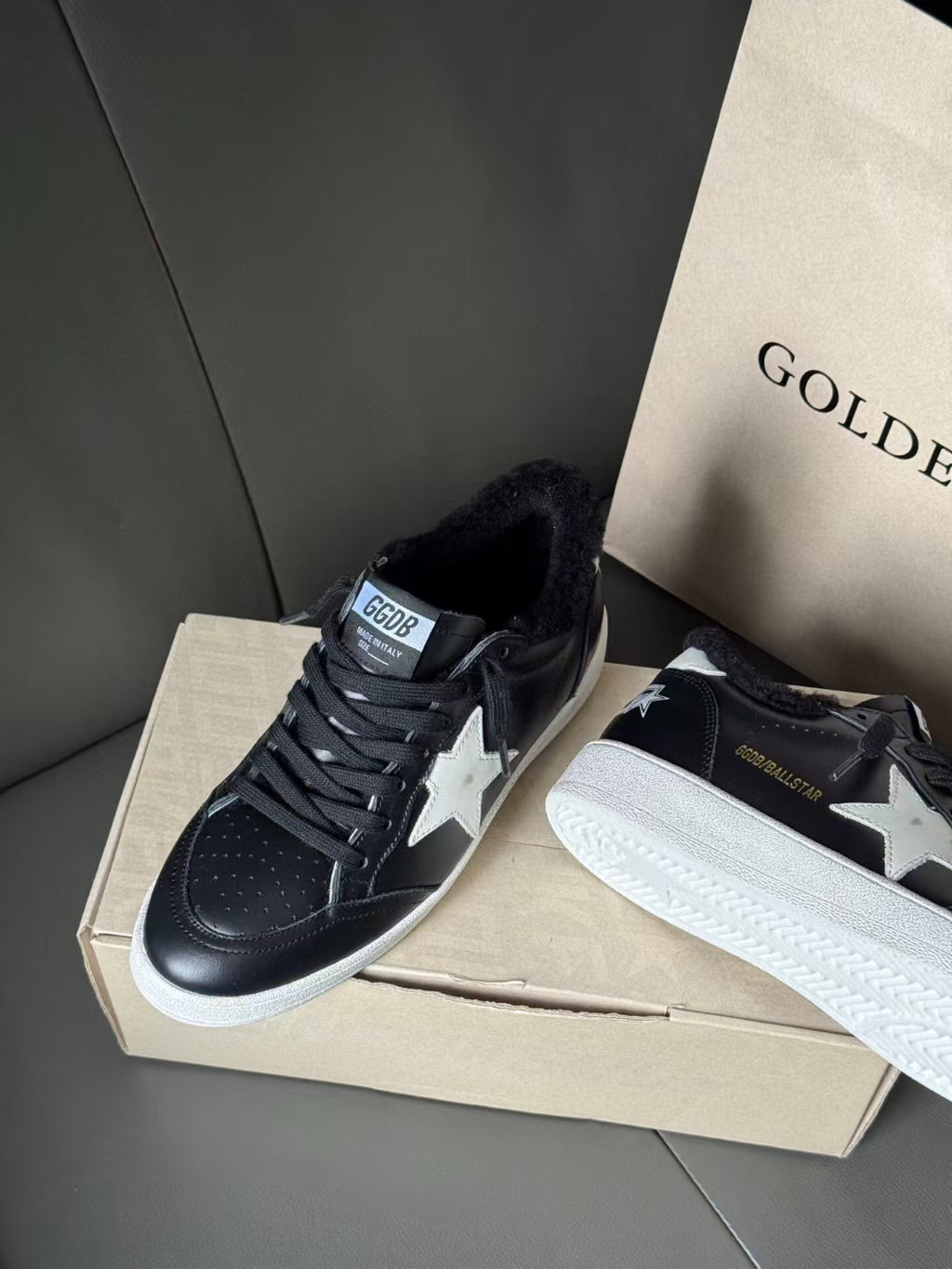 Black leather sneakers with white star accents and textured toe detail