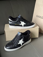 Black low-top sneakers with white star patch, lace-up front, white rubber sole